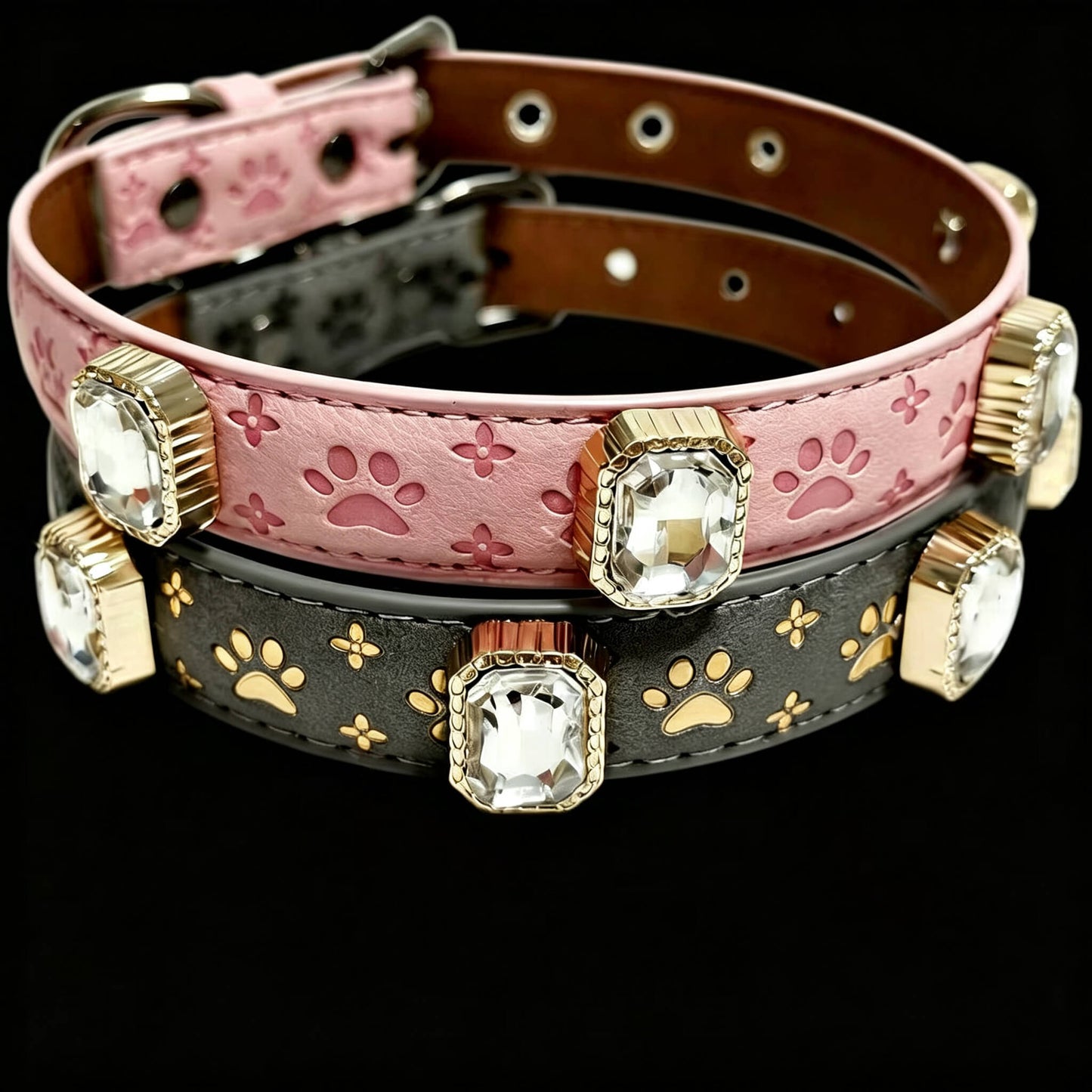 Two dog collars with paw prints and gemstones on a black background