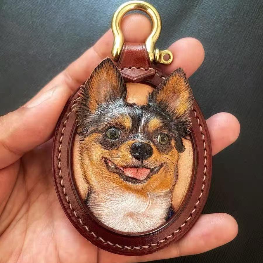 Custom Leather Oval Pet Portrait Keychain with a dog's face design held in a hand against a dark background