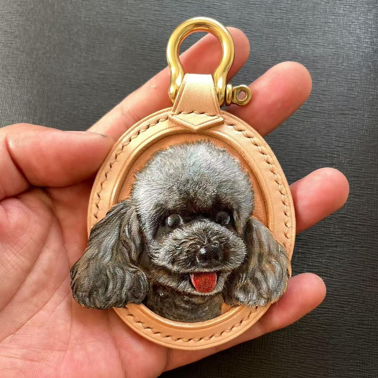 Custom Leather Oval Pet Portrait Keychain with a dog's face design held in a hand against a dark background