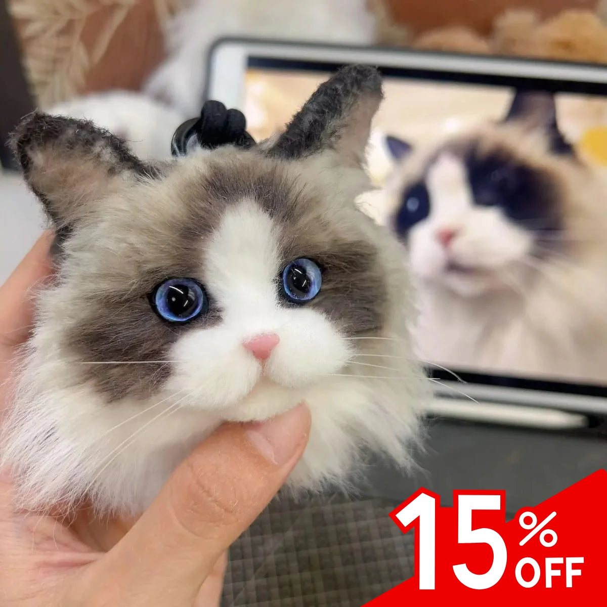 Toy cat with blue eyes held by a hand, with a blurred background and 15% off text overlay.