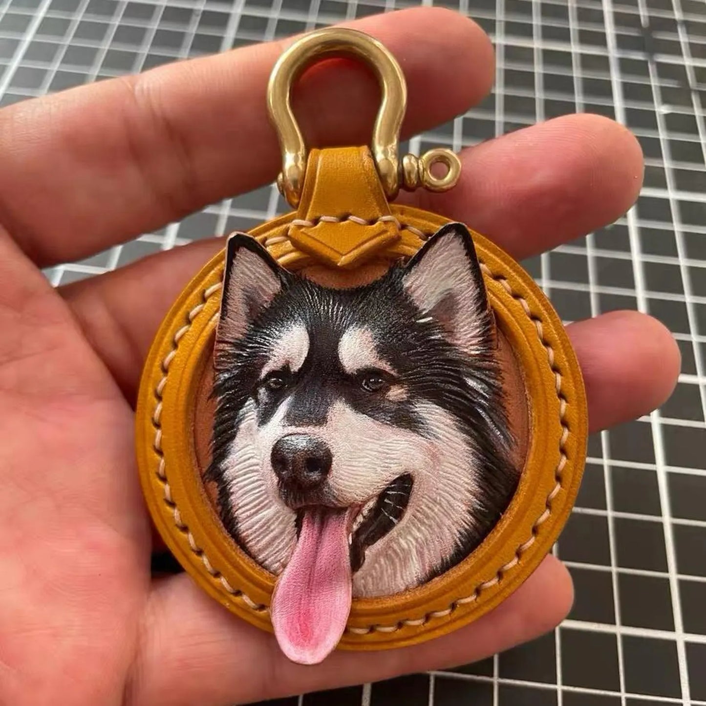 Custom Leather Pet Portrait Keychain with a dog's face design held in a hand against a beige background