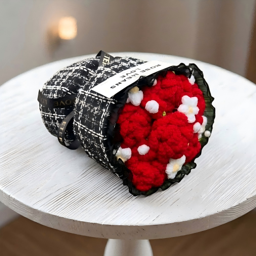 Black and white patterned bag with a red and white floral arrangement on a white surface.