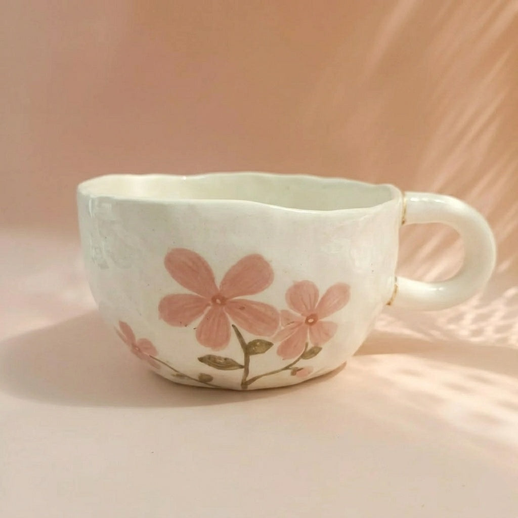 Ceramic mug with pink floral design on a soft pink background