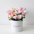 Crocheted flowers in a white container with 'The Rosemadam' branding on a light background
