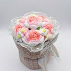 Crocheted pink flowers in a textured pot with a white label on a light gray background
