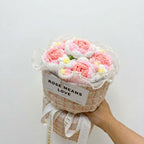 Bouquet of crocheted flowers in a textured container with 'ROSE MEANS LOVE' text on a light gray background.