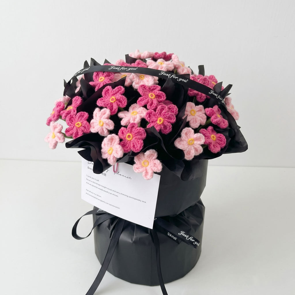 Bouquet of pink flowers wrapped in black paper with a card on a white background