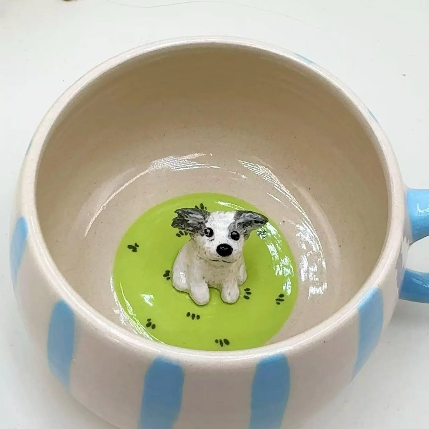 Custom ceramic mug with blue stripes and a small dog figurine inside on a white background