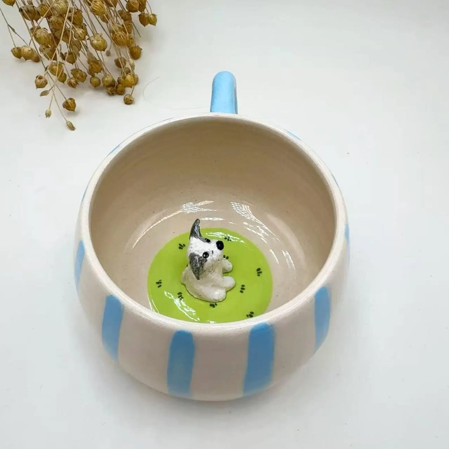 Custom ceramic mug with blue stripes and a small dog figurine inside on a white background
