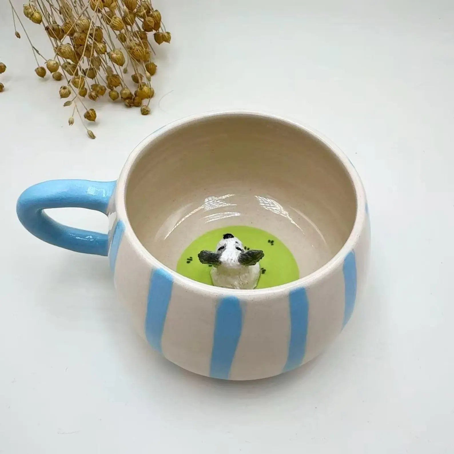 Custom ceramic mug with blue stripes and a small dog figurine inside on a white background