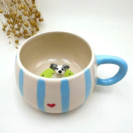 Custom ceramic mug with blue stripes and a small dog figurine inside on a white background