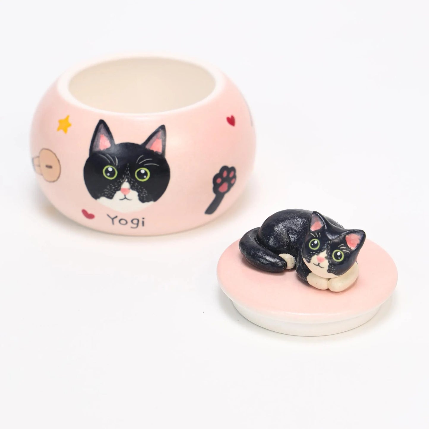 Custom pink ceramic urn with black cat design and 'Yogi' text on a white background