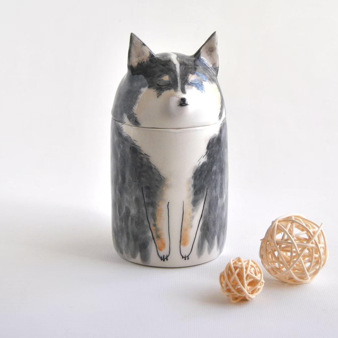Cat-shaped ceramic jar on a white background with decorative balls.